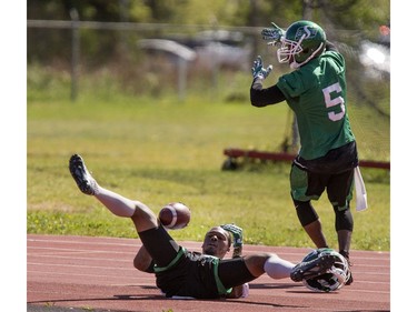 Wide receiver Ricky Collins lost his helmet after crashing into the track on play broken up by defensive back Derrius Brooks during Roughrider training camp at Griffiths Stadium, June 15, 2016.