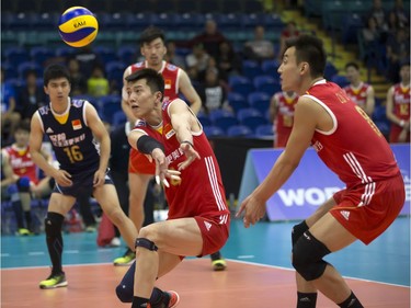 Chen Zhang of China (C), with teammate Jianjun Cui (R), returns service against Portugal during FIVB World Volleyball League action at Sasktel Centre in Saskatoon, June 24, 2016.