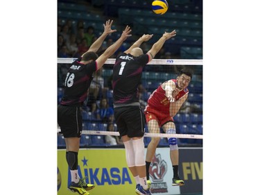 QingYao Dai of China (R) hits the ball off the block of Portugal players #18 Andre Reis Lopes and Marcel Keller Gil during FIVB World Volleyball League action at Sasktel Centre in Saskatoon, June 24, 2016.