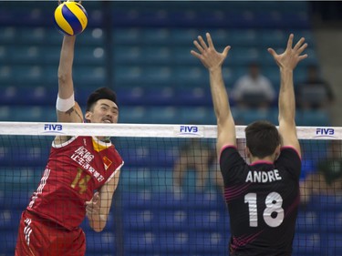 QingYao Dai of China (L) spikes the ball at Portugal player Andre Reis Lopes during FIVB World Volleyball League action at Sasktel Centre in Saskatoon, June 24, 2016.