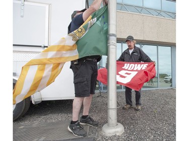 SaskTel Centre Coliseum operators Gary Musty (L) and Dale Turta raise a Gordie Howe flag and set all other flags to half-mast outside of Sasktel Centre in Saskatoon, June 10, 2016. Howe passed away today at the age of 88.