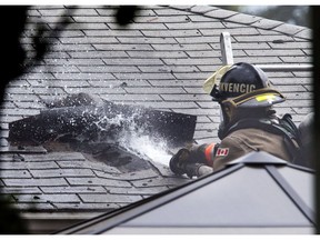 A Saskatoon firefighter aims water into a hole cut into the roof at 2232 Ewart Avenue while battling a house fire on July 1, 2016.