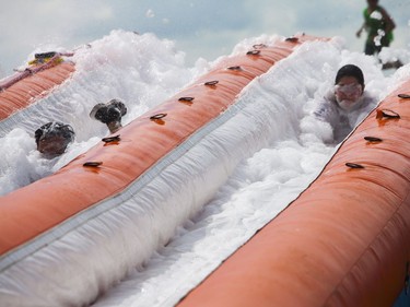 Diane San-Juan (R) slides down an obstacle during the 5K Foam Fest run near Pike Lake, July 2, 2016.