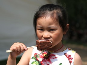 Cici Hu, 6, eats cheesecake on a stick on the last day of Taste of Saskatchewan in Saskatoon on July 17, 2016.