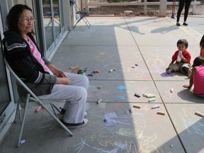 Red Earth First Nation evacuee Verna McKay sits outside of the Henk Ruys Soccer Centre surrounded by chalk drawings in Saskatoon July 17, 2016.