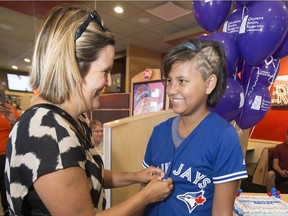 Bella Arcand-Lafond, 11 years old, who had radical brain surgery several years ago, tries on a Blue Jays jersey with help from Mom Bev Lafond, which she received after she found out she'll throw out the first pitch at a Blue Jays baseball game.