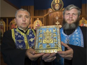 Father Florin Soane, left, and Father Andre Maier hold a scaled copy of the Kursk-Root icon at St. Vincent of Lerins Orthodox Church, Monday, July 25, 2016. The real icon, which dates from the 13th century, is one of the most important icons in the Russian Orthodox Church and will be in Saskatoon on Wednesday.