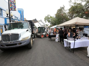 Workers finish up the final road repairs as booths get set up at the 2016 PotashCorp Fringe Theatre and Street Festival on Broadway Avenue, July 28, 2016.