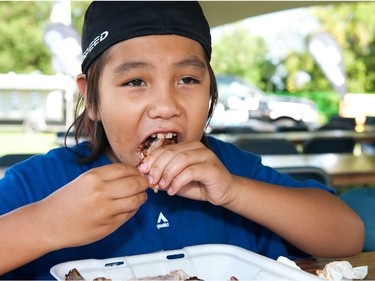 Teyshaun Seesequasis, 8, of Beardy's and Okemasis First Nation chows down on some ribs during Saskatoon Ribfest at Diefenbaker Park in Saskatoon on July 29, 2016.