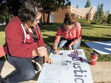 Sabrina Moccasin-Cuthand (L) and Rachel Cuthand make a sign during a rally for Colten Boushie outside of the Saskatchewan Provincial Court in North Battleford, August 18, 2016. People rally outside a Saskatchewan courthouse Thursday where a farmer accused of fatally shooting a First Nations man is to make an appearance.