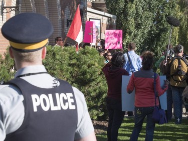 An RCMP officer looks on as family and friends of Colten Boushie rally outside of the Saskatchewan Provincial Court in North Battleford where a farmer accused of fatally shooting a First Nations man is to made appearance, August 18, 2016.