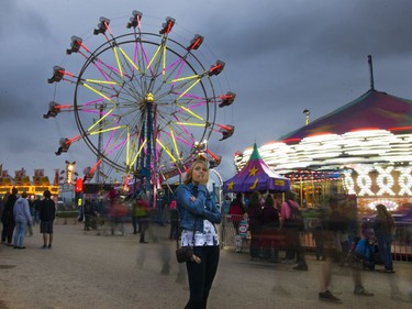 A fairgoer stops to watch a ride at the Saskatoon Ex, where West Coast Amusements lights up the midway on a dark cloudy evening, August 10, 2016.