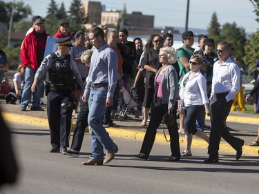 RCMP members escort a family across the street from North Battleford Provincial Court to the detachment through hundreds of protesters chanting "Justice For Colten," Colten Boushie, the 22-year-old that was fatally shot last week allegedly by Gerald Stanley, August 18, 2016.
