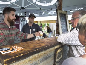 Derek Sandercock, left, serves a couple at the Black Bridge Brewery tent during YXE Beer Fest in Rotory Park, August 26, 2016.