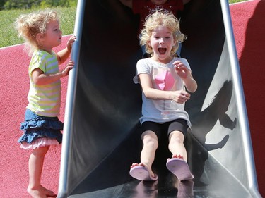 Celah Bodrug watches as her siblings Alethia Bodrug and Tobiash Bodrug fly down the Kinsmen Park slide in Saskatoon on Aug. 2, 2016.