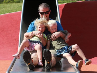 Nathan Bodrug and his children Celah and Nikaio fly down the Kinsmen Park slide in Saskatoon on Aug. 2, 2016.