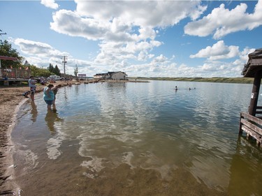 People swim around a gazebo that sits underwater at the beach in Manitou Beach, SK on Friday, August 5, 2016.