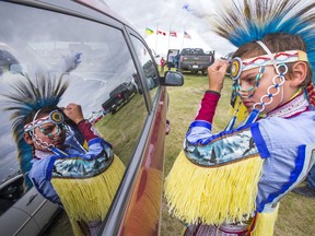Kole Poochay of Yellowquill First Nation uses his reflection in the side of a van window as he readies for day two of Wanuskewin Days Cultural Celebration and Powwow at Wanuskewin Heritage Park, August 24, 2016.