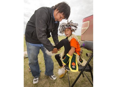 Ritchie Whitefish helps grandson Dayton Thomas get ready for the Grand Entry on day two of Wanuskewin Days Cultural Celebration and Powwow at Wanuskewin Heritage Park, August 24, 2016.