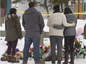 People come to lay a wreath and flowers at a roadside memorial in front of the La Loche Community School,  Wednesday, January 27, 2016.