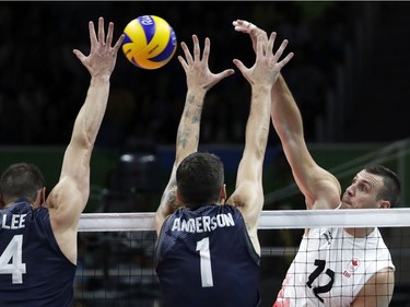 United States' David Lee, left, Matthew Anderson, center, attempt to block a ball spiked by Canada's Gavin Schmitt, right, during a men's preliminary volleyball match at the 2016 Summer Olympics in Rio de Janeiro, Brazil, Sunday, Aug. 7, 2016.