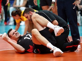 Gavin Schmitt #12 of Canada is helped by a trainer after being injured against Russia during the Men's Quarterfinal Volleyball match on Day 12 of the Rio 2016 Olympic Games at Maracanazinho on August 17, 2016 in Rio de Janeiro, Brazil.