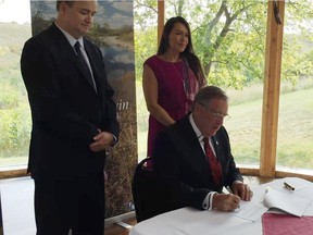 Wanuskewin CEO Dana Soonias, from left, and Wanuskewin Board Chair Candace Wasacase-Lafferty look on while Saskatoon mayor Don Atchison signs the 99-year lease agreement giving Wanuskewin Heritage Park 375 acres of city-owned land adjacent to the park. Jeff Losie/Saskatoon StarPhoenix