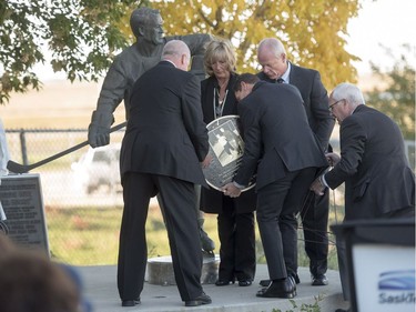 Saskatoon Funeral Home director Bill Edwards, right, directs, Cathy Howe, daughter of Mr. Hockey Gordie Howe, her brothers Marty, Mark, and Murray place a plaque at the base of a Statue of Gordie Howe, where his remains where interned during a memorial service outside Sasktel Centre in Saskatoon, Sunday, September 25, 2016.