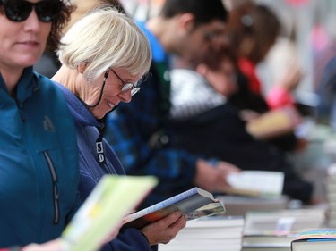 A woman checks out Alice Kuiper's book 'The Death of Us' for sale at the Word on the Street festival in Saskatoon on September 18, 2016 .