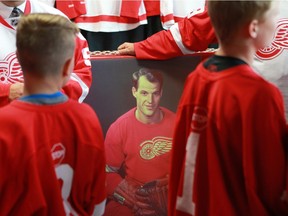 Saskatoon Red Wings hockey players surround a photo of Gordie Howe during a Tuesday press conference.