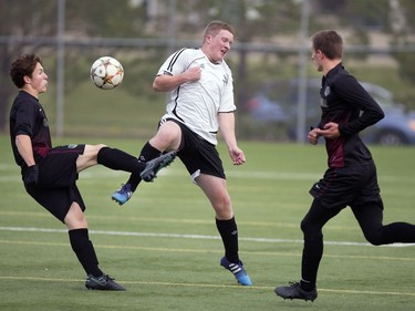 Ashton Hinz of St. Joseph High School Guardians (C) goes against Fraser McLeod (L) and teammate Zach Edwards of the Centennial Chargers during high school soccer action at the SaskTel Soccer Centre, September 12, 2016.