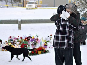 Residents console each other at the memorial near the La Loche Community School in La Loche, Sask., on Sunday. January 24, 2016. A shooting Friday left four people dead. THE CANADIAN PRESS/Jason Franson