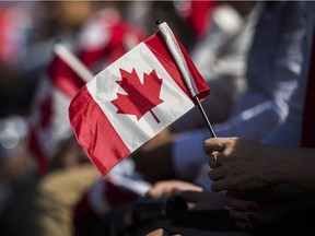 A person holds a flag during a Canadian citizenship ceremony at the in the World Cup of Hockey Fan Village in Toronto, Tuesday, September 20, 2016.