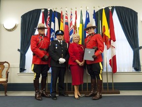 Const. Elmer Russell, left, correctional officer Ronald Minter, center left, and Const. Tyler Zrymiak, right, stand with Lieutenant Governor Vaughn Solomon Schofield, center right, during the Investiture of Bravery Awards at Government House in Regina, Saskatchewan on Monday October 17, 2016. The trio were awarded bravery medals for their response to a May 2013 high-speed chase in which a conservation officer was killed and a man was pulled from a burning vehicle.