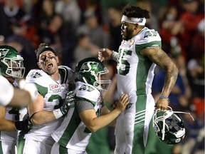 The Saskatchewan Roughriders' Kacy Rodgers, right, and Bryn Roy, left, celebrate with kicker Tyler Crapigna, middle, after his game-winning field goal in overtime Friday against the Ottawa Redblacks.