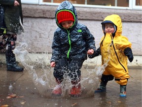 One-year-old Beau Parker watches his three-year-old brother Elwood Parker make a big splash, nearly soaking a passerby, by jumping in a huge puddle on Princess Street during a rainy Sunday in Saskatoon on October 16, 2016.