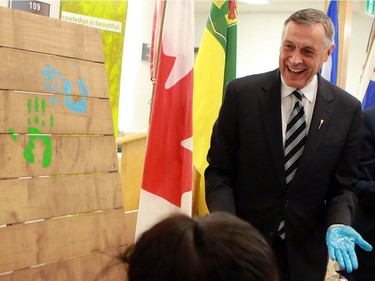 Education minister Don Morgan stamps his handprint on a board during the official opening of the newest USSU childcare centre at the McEown location in Saskatoon on October 17, 2016.