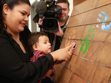 University of Saskatchewan student Jocelyn Arcand helps her son stamp his handprint on a board during the official opening of the newest USSU childcare centre at the McEown location in Saskatoon on October 17, 2016.