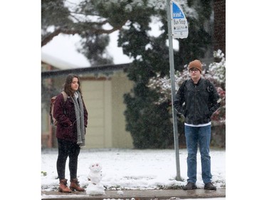 Abby Holtslander and Caleb Coupland wait for a bus next to a small snowman that someone built in Saskatoon on October 5, 2016.