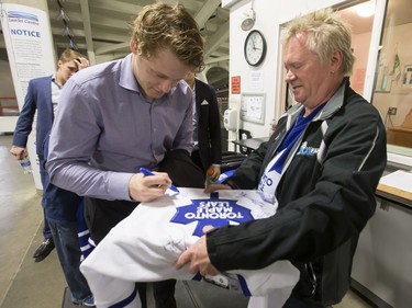 Morgan Rielly of the Toronto Maple Leafs (L) signs a jersey for Matt Bradley following a pre-game skate at SaskTel Centre before facing the Ottawa Senators, October 4, 2016.