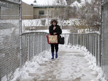 A woman crosses the pedestrian overpass on College Drive at Campus Drive in a heavy, wet snow from a major weather system that left Saskatoon residents shovelling, walking and driving in slippery conditions, October 5, 2016.  Intermittent power outages affected traffic lights and created backups.