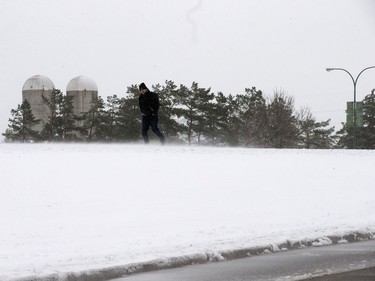 A person walks in the snow along College Drive as a heavy, wet snow from a major weather system left Saskatoon residents shovelling, walking and driving in slippery conditions, October 5, 2016.  Intermittent power outages also affected traffic lights and created backlogs.