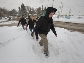 People posthole through a huge drift on what should be a sidewalk on 108th Street at Circle Drive as they make their  way towards the university, Thursday, October 06, 2016. More snow slow pedestrians and traffic.