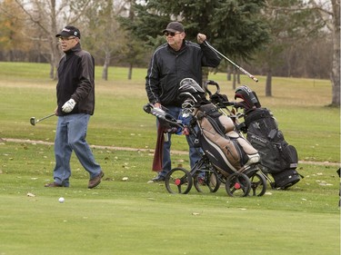 Lloyd Gunther (L) Ron McPherson and Glen Gunther (not shown) tough out a round of golf at plus two degrees Celsius on the Wildwood Golf Course, October 19, 2016.