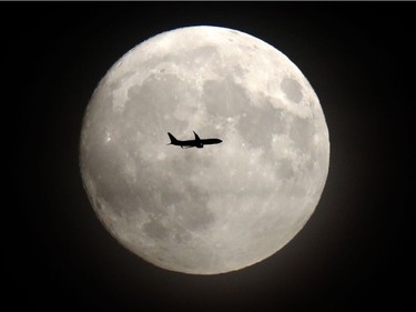 A commerical jet flies in front of the moon on its approach to Heathrow airport in west London on November 13, 2016. Tomorrow, the moon will orbit closer to the earth than at any time since 1948, named a 'supermoon,' it is defined by a Full or New moon coinciding with the moon's closest approach to the Earth.