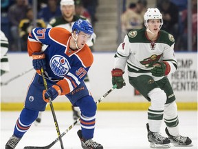 Edmonton Oilers' Connor McDavid moves the puck against Minnesota Wild's Mike Reilly during the second period of an NHL pre-season hockey game in Saskatoon, Saturday, September 26, 2015.