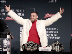 Conor McGregor, center, reacts after taking his opponent Eddie Alvarez's title from a table to put it on his side during a news conference ahead of the UFC 205 mixed martial arts fights, Thursday, Nov. 10, 2016, at Madison Square Garden in New York as UFC president Dana White, left, and fighter Stephen Thompson, right, react. McGregor and Alvarez will fight each other while Thompson will fight Tyron Woodley on Saturday.
