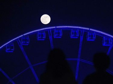 People watch as a supermoon is seen rising beyond a ferris wheel in Hong Kong on November 14, 2016. Skygazers headed to high-rise buildings, ancient forts and beaches on November 14 to witness the closest "supermoon" to Earth in almost seven decades, hoping for dramatic photos and spectacular surf. The moon will be the closest to Earth since 1948 at a distance of 356,509 kilometres, creating what NASA described as "an extra-supermoon."