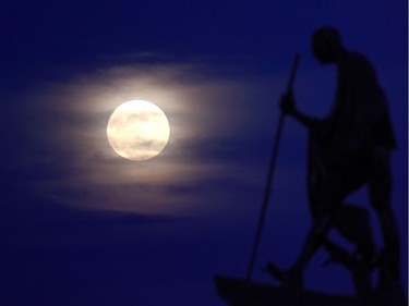 A supermoon rises behind the a statue of Mahatma Gandhi at Marina Beach in Chennai on November 14, 2016. Skygazers headed to high-rise buildings, ancient forts and beaches on November 14 to witness the closest "supermoon" to Earth in almost seven decades, hoping for dramatic photos and spectacular surf. The moon will be the closest to Earth since 1948 at a distance of 356,509 kilometres, creating what NASA described as "an extra-supermoon."