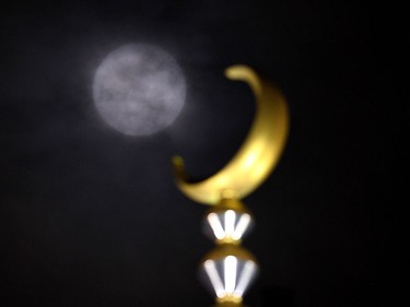 A supermoon is seen obscured by clouds next to a crescent atop a mosque in Kuala Lumpur on November 14, 2016. Skygazers headed to high-rise buildings, ancient forts and beaches on November 14 to witness the closest 'supermoon' to Earth in almost seven decades, hoping for dramatic photos and spectacular surf. The moon will be the closest to Earth since 1948 at a distance of 356,509 kilometres, creating what NASA described as "an extra-supermoon."